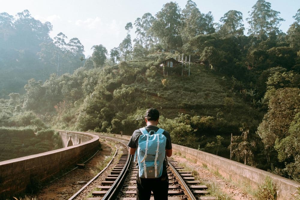 A hiker walking the railway tracks through the misty hills above Ella